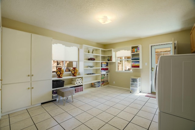 interior space featuring laundry area, light tile patterned floors, and a textured ceiling