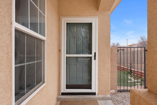 property entrance featuring fence and stucco siding