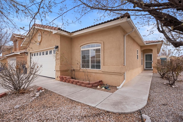 view of front facade featuring a garage, driveway, a tile roof, and stucco siding