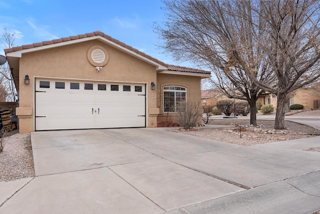 view of front of house with a garage, driveway, a tiled roof, and stucco siding