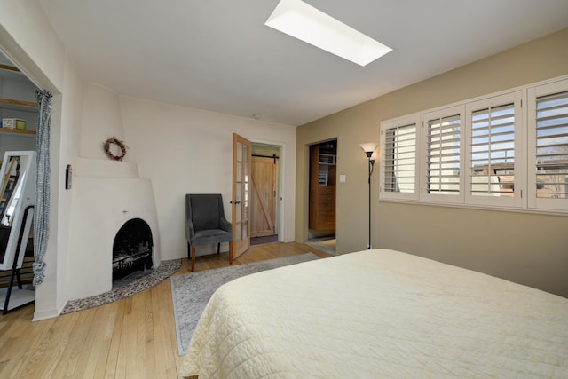 bedroom with a skylight, wood finished floors, and a barn door