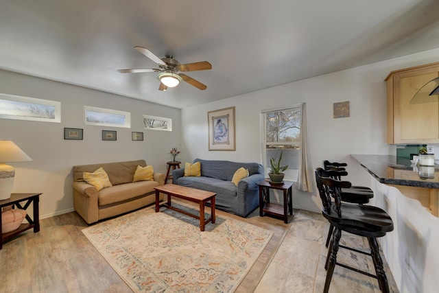 living room featuring light wood-style floors, baseboards, and a ceiling fan