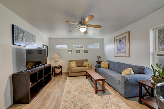 living area with wood finished floors, a ceiling fan, and baseboards