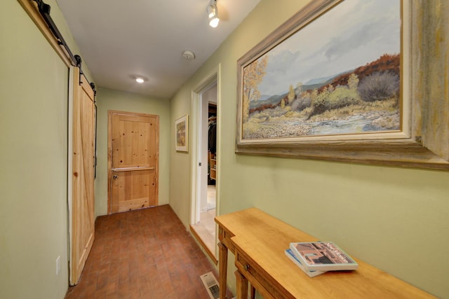 hallway with brick floor, a barn door, and visible vents