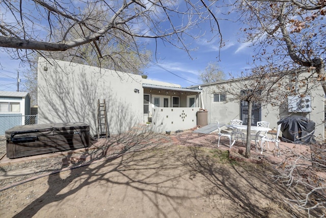 exterior space featuring a patio area, a hot tub, fence, and stucco siding