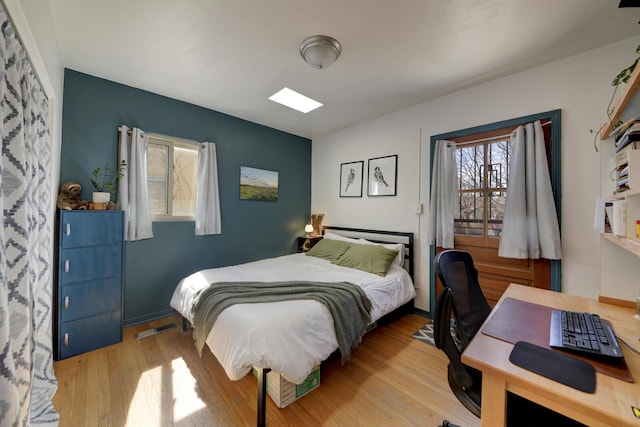 bedroom featuring multiple windows, wood finished floors, visible vents, and baseboards