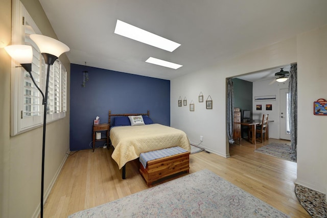 bedroom with lofted ceiling with skylight, baseboards, and wood finished floors