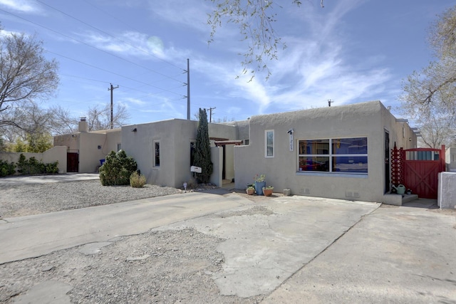 rear view of property featuring fence, a gate, and stucco siding