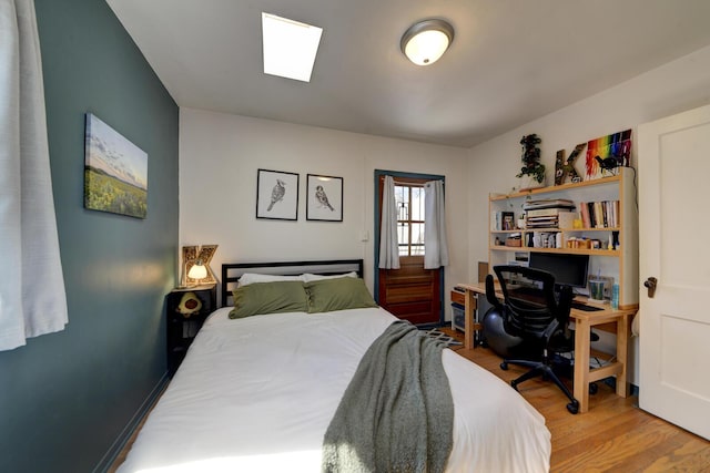 bedroom with a skylight and wood finished floors