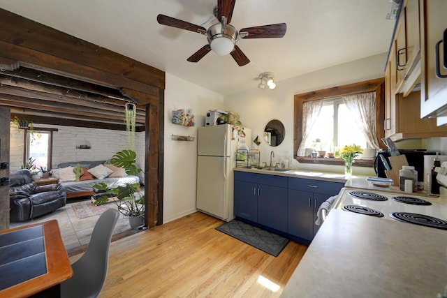 kitchen with light wood finished floors, a wealth of natural light, blue cabinetry, and freestanding refrigerator