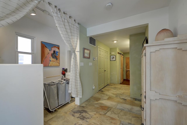 corridor featuring stone finish flooring and visible vents