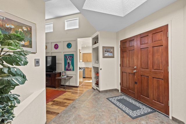 foyer with visible vents, baseboards, wood finished floors, and vaulted ceiling