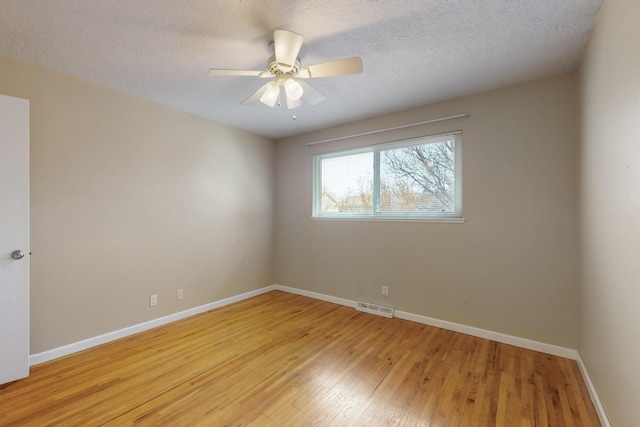 empty room featuring light wood-type flooring, visible vents, baseboards, and a textured ceiling