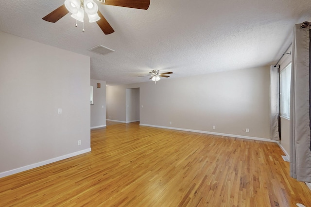 empty room featuring visible vents, a textured ceiling, light wood-style floors, baseboards, and ceiling fan