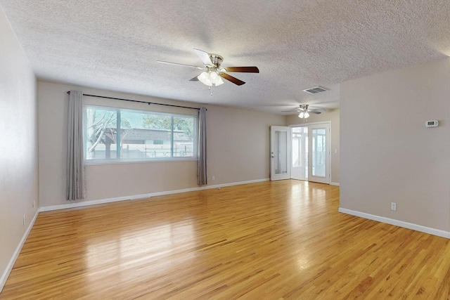 spare room with visible vents, a textured ceiling, light wood-type flooring, and baseboards