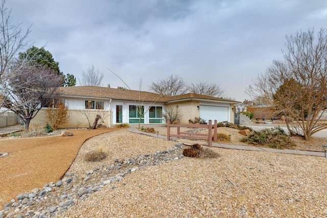 single story home featuring brick siding, an attached garage, and fence