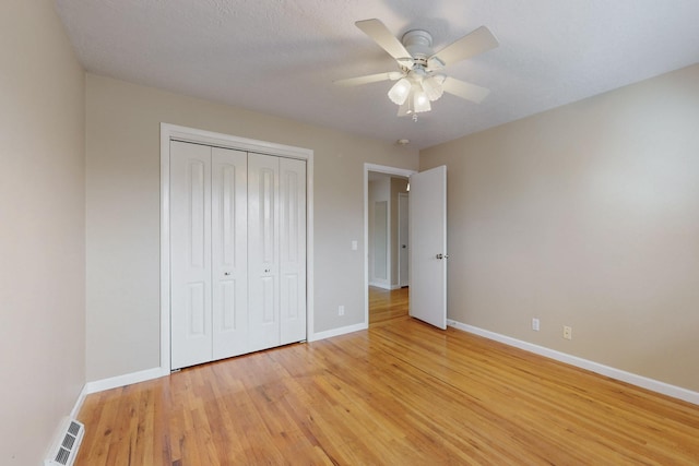 unfurnished bedroom with light wood finished floors, visible vents, ceiling fan, baseboards, and a closet