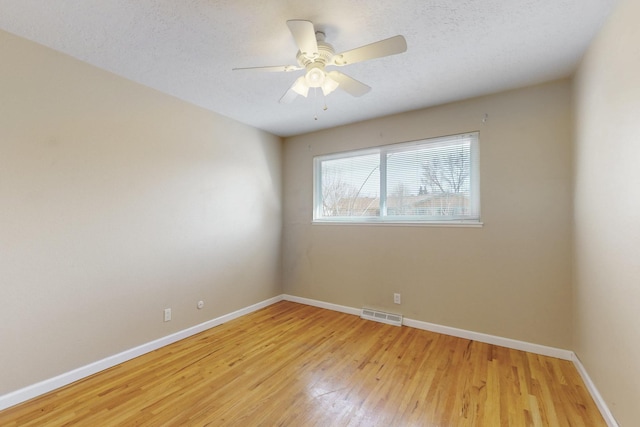 spare room with baseboards, visible vents, ceiling fan, a textured ceiling, and light wood-type flooring