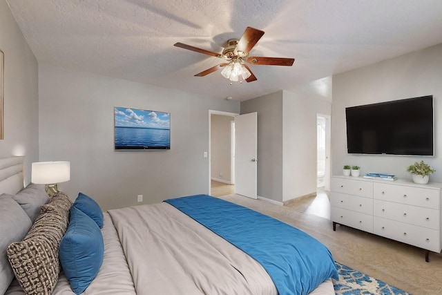 bedroom featuring a ceiling fan, a textured ceiling, connected bathroom, baseboards, and light colored carpet