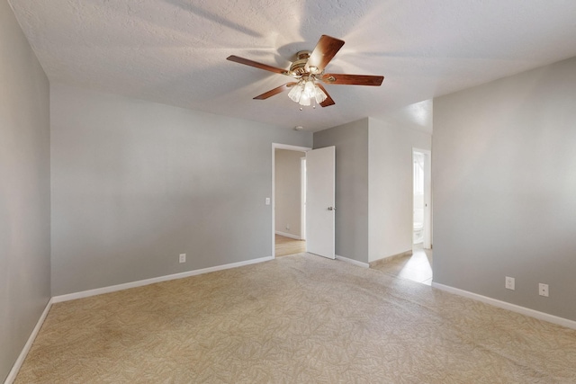 unfurnished room featuring baseboards, a textured ceiling, light carpet, and ceiling fan