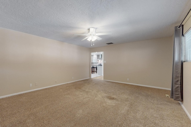 spare room with visible vents, light carpet, a textured ceiling, baseboards, and ceiling fan