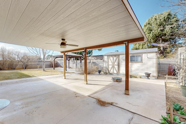 view of patio / terrace featuring a gazebo, a fenced backyard, a ceiling fan, and an outdoor structure