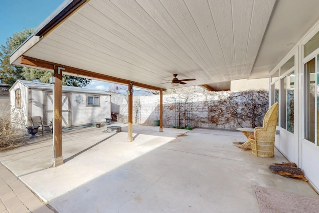 view of patio with an outbuilding, ceiling fan, and fence