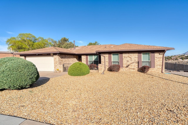 ranch-style house with an attached garage, fence, brick siding, and driveway