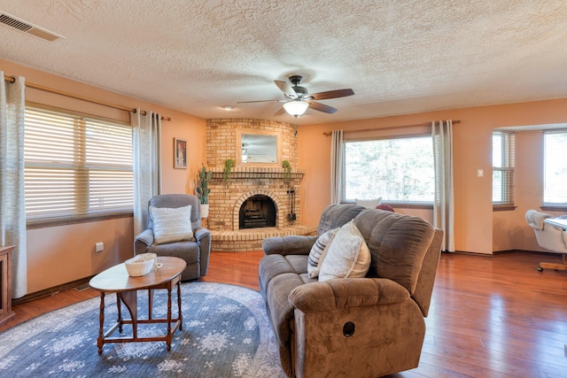 living room with wood finished floors, plenty of natural light, a fireplace, and visible vents