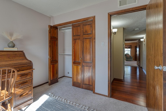 unfurnished bedroom with baseboards, visible vents, carpet floors, and a textured ceiling