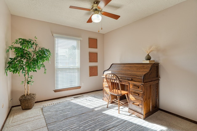 carpeted office featuring baseboards, a textured ceiling, and ceiling fan