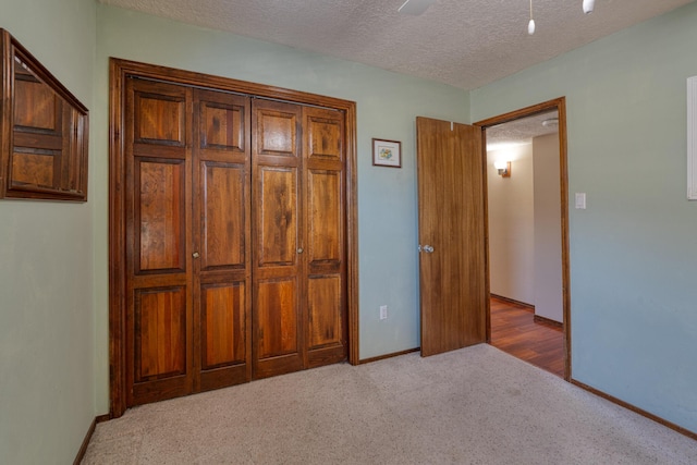 unfurnished bedroom featuring baseboards, carpet floors, a textured ceiling, and a ceiling fan