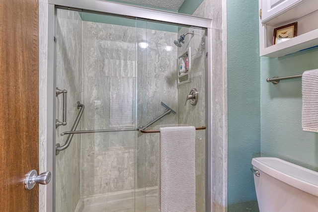 bathroom featuring a stall shower, toilet, and a textured wall