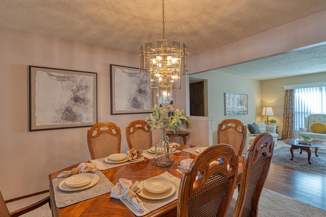 dining space featuring a textured ceiling, an inviting chandelier, and wood finished floors