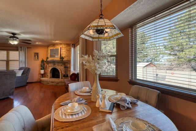 dining room featuring a wealth of natural light, a textured ceiling, wood finished floors, and a fireplace