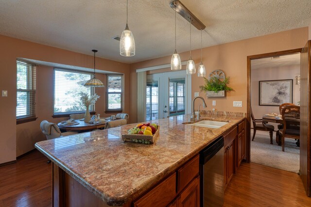 kitchen featuring stainless steel dishwasher, wood finished floors, brown cabinetry, and a sink