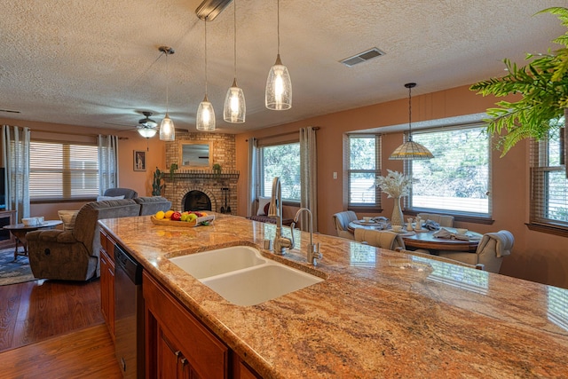 kitchen featuring visible vents, a sink, open floor plan, a fireplace, and stainless steel dishwasher