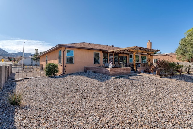 rear view of property featuring stucco siding, a fenced backyard, a mountain view, a chimney, and a patio area