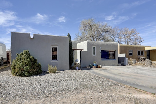 pueblo-style house with cooling unit and stucco siding