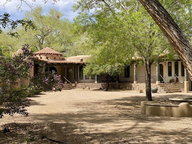 view of front of property with stucco siding, a tiled roof, and covered porch