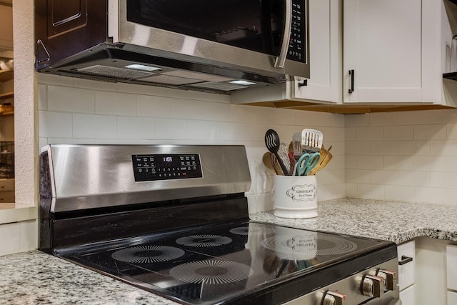 details featuring decorative backsplash, appliances with stainless steel finishes, white cabinetry, and light stone countertops