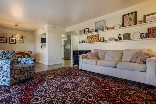 living area with wood finished floors, visible vents, and baseboards