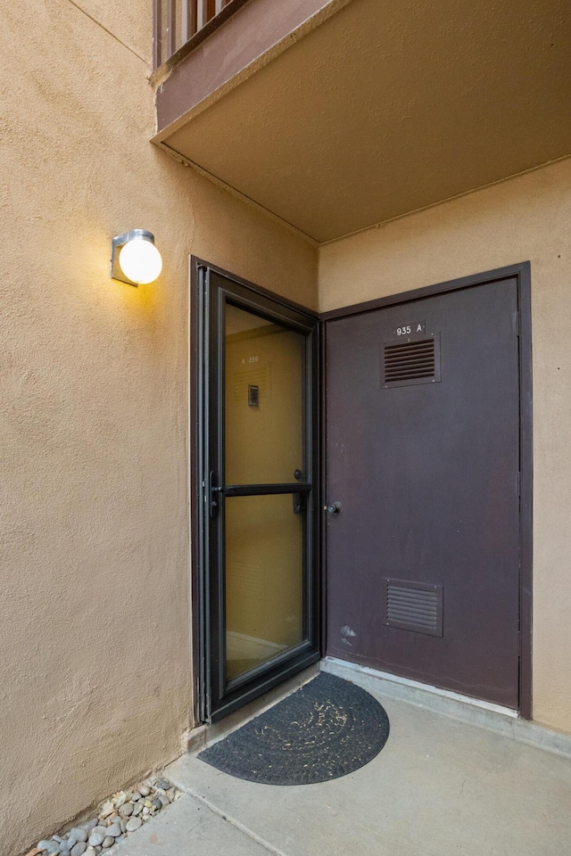 entrance to property featuring visible vents and stucco siding