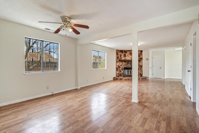 unfurnished living room with a fireplace, wood finished floors, visible vents, and baseboards