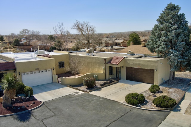 southwest-style home with stucco siding, driveway, and a tile roof