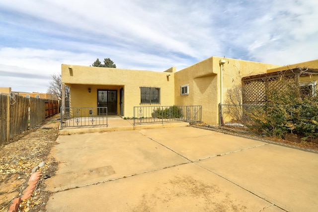 back of property with stucco siding, a patio area, and fence