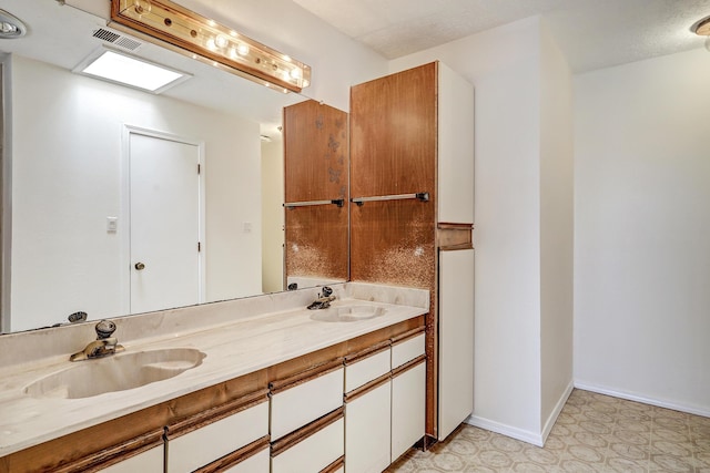 bathroom with a sink, visible vents, double vanity, and tile patterned floors