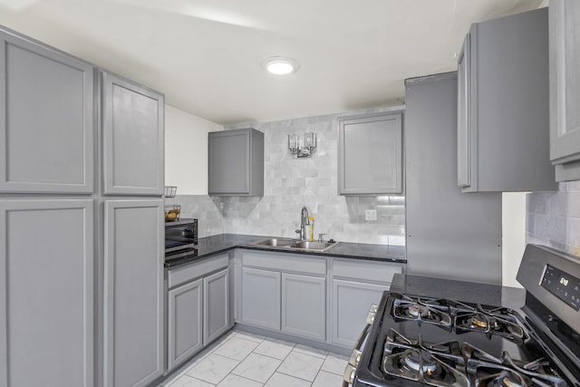 kitchen with marble finish floor, gray cabinets, a sink, backsplash, and appliances with stainless steel finishes