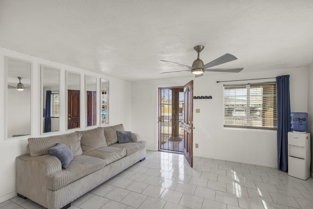 living area featuring a ceiling fan and baseboards