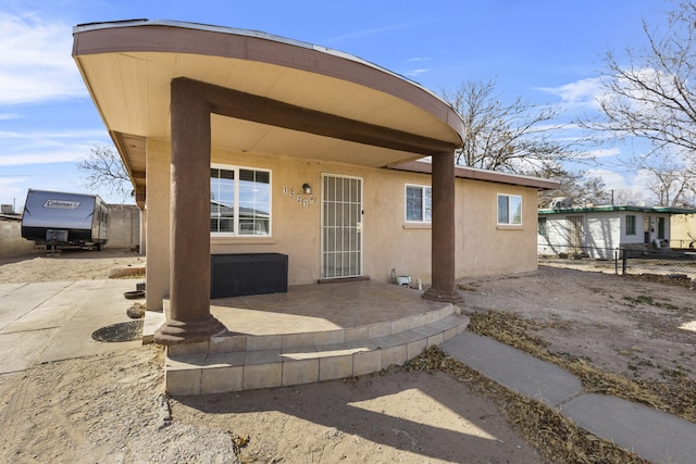 rear view of house with a patio area, fence, and stucco siding